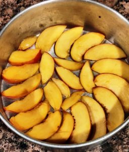 Arrange peach slices in baking tin